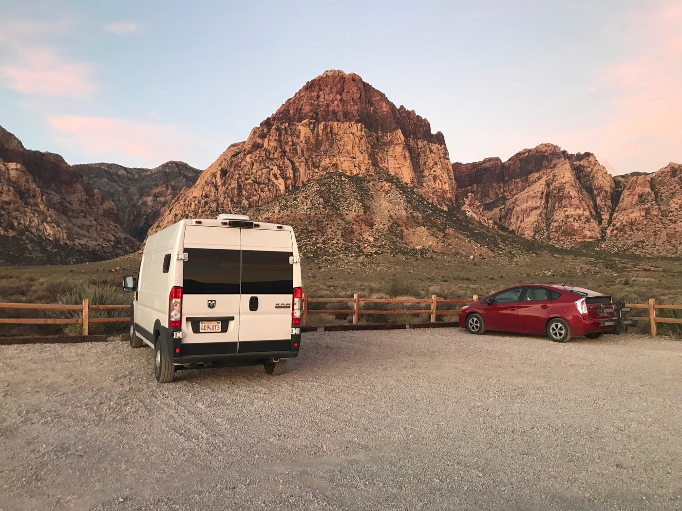  prepped for delicious baking.|Fresh chocolate chip cookies cooling on a wooden board in a compact RV kitchen. Perfect for your next RV rental adventure!|White RV rental van parked on a dirt road amid tall pine trees under clear blue sky — photo 4