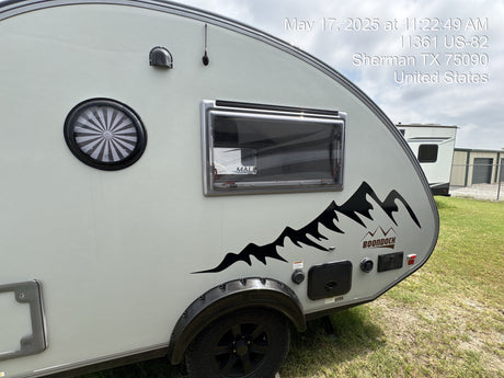Side exterior view of a grey teardrop Boondock RV with a mountain decal. Perfect for an rv rental, parked outdoors in Sherman, TX.