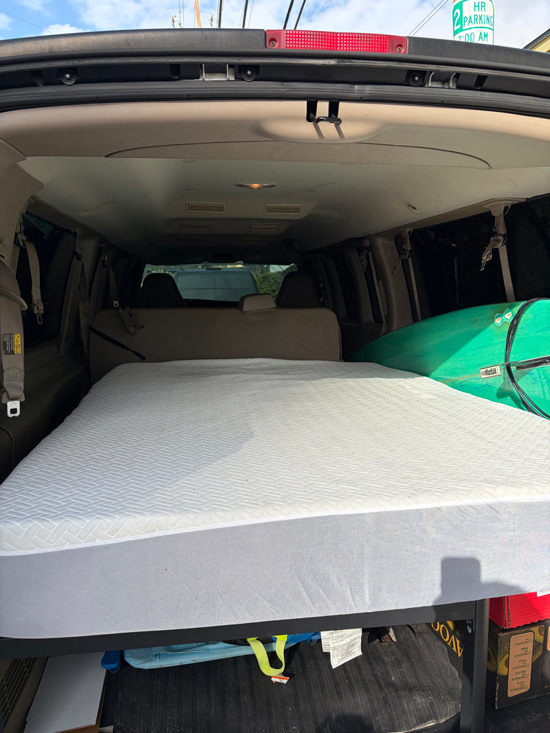 Cozy RV rental setup in a converted van, featuring a mattress, surfboard, and organized storage for travel. — photo 4