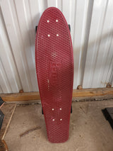 Red Penny skateboard leans by a corrugated metal shed wall, ready for an RV rental adventure or outdoor recreation.