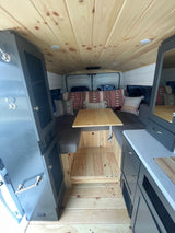 RV rental: Custom camper van interior with wood finishes, comfy seating, and built-in kitchen area.