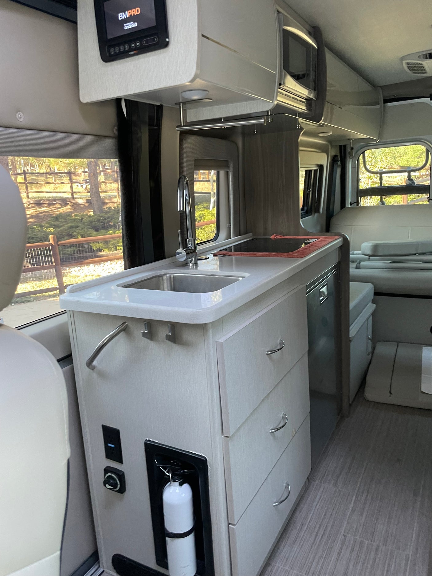 Well-equipped RV rental interior: compact kitchen with sink, microwave, and tech controls. Perfect for mobile living.
