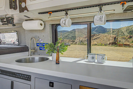 RV rental van life kitchen: sink, storage, and a stunning mountain view from the window. Perfect for adventures.