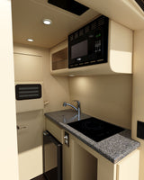 Inside an RV rental: a well-equipped compact kitchen with microwave, sink, electric cooktop, and fridge.