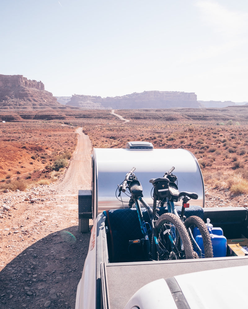 RV rental adventure: Pickup truck hauls bikes and a teardrop trailer down a desert dirt road amidst red rock formations. — photo 17