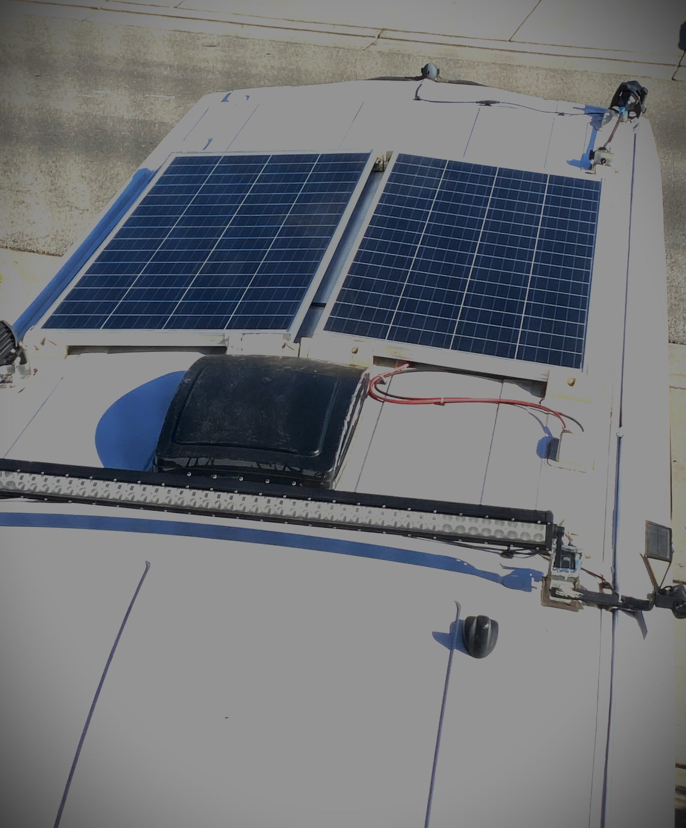 Rooftop of an RV rental: features solar panels, a vent fan, and an LED light bar for off-grid power and lighting.