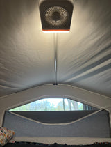 Inside an RV rental camper: Overhead fan with light, ceiling structure, and window view of trees from the sleeping area.