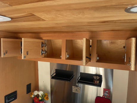 RV rental kitchen: Open wooden overhead cabinets & stainless steel wall with magnetic shelves offer smart storage solutions.