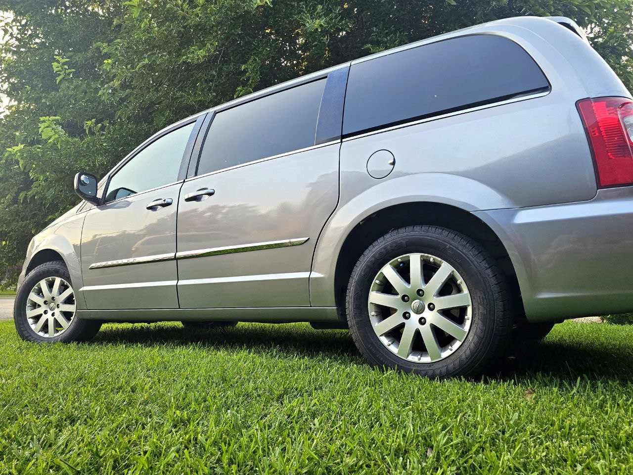 Side view of a grey minivan parked on green grass. Ideal for family travel. Check out options like this or an RV rental. — photo 3