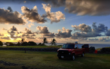 Red van RV rental at sunset by the ocean, ready for scenic travel. Ideal for a beautiful road trip.