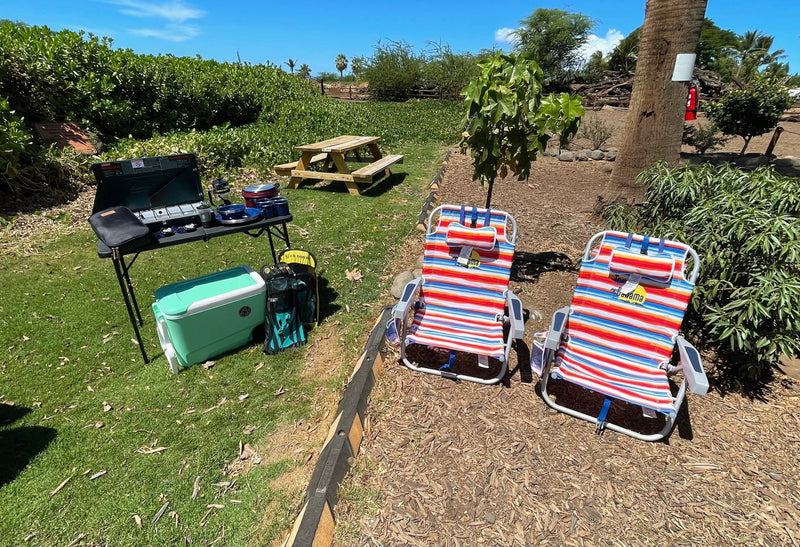 Sunny outdoor setup for your RV rental: portable kitchen, cooler, picnic table, and comfy striped lounge chairs. — photo 10