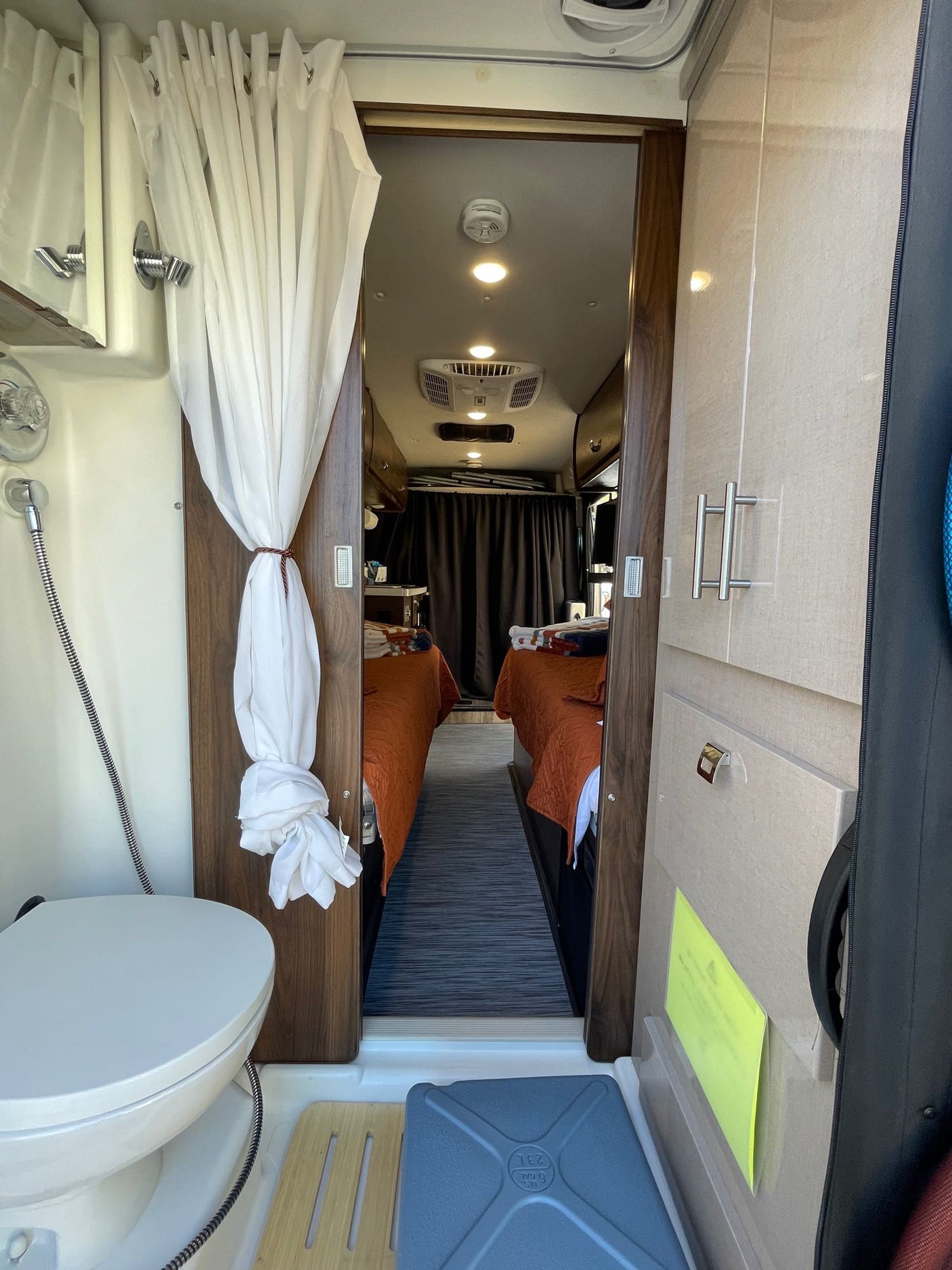 Explore this RV rental's compact interior, featuring a bathroom with shower/toilet and a sleeping area with twin beds.