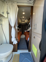 Explore this RV rental's compact interior, featuring a bathroom with shower/toilet and a sleeping area with twin beds.