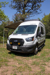 White Ford Transit camper van RV rental with awning extended, perfect for outdoor camping.