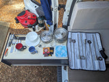 RV rental camping kitchen setup: portable grill, Solo Stove cookware, utensils, and skewers, ready for outdoor meals.