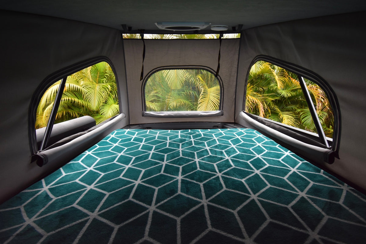 Inside a pop-top RV rental, a comfy bed with teal blanket offers tropical palm views from wide windows. Adventure awaits! — photo 20