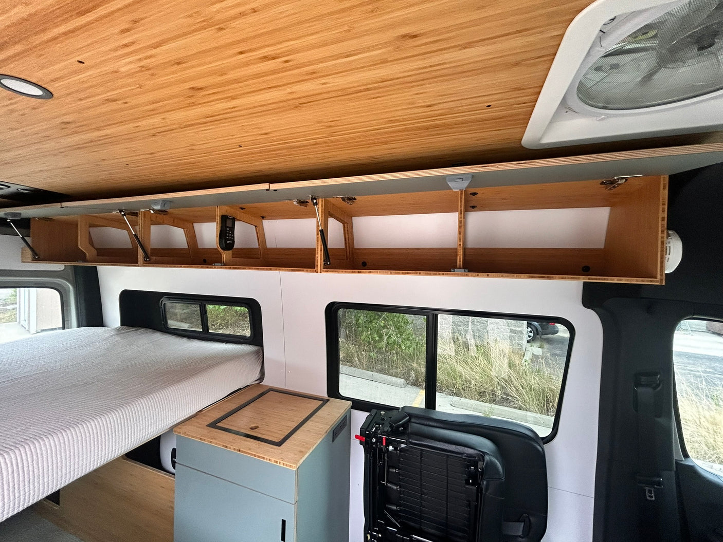 Inside this modern RV rental: cozy bed, stylish wood ceiling, and ample storage for your adventure.