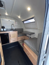 Compact RV rental interior featuring a modern kitchen, cozy dinette, and practical storage solutions.