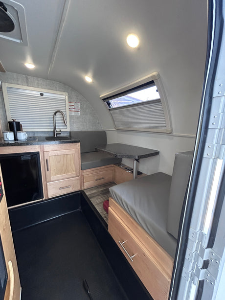 Compact RV rental interior featuring a modern kitchen, cozy dinette, and practical storage solutions.