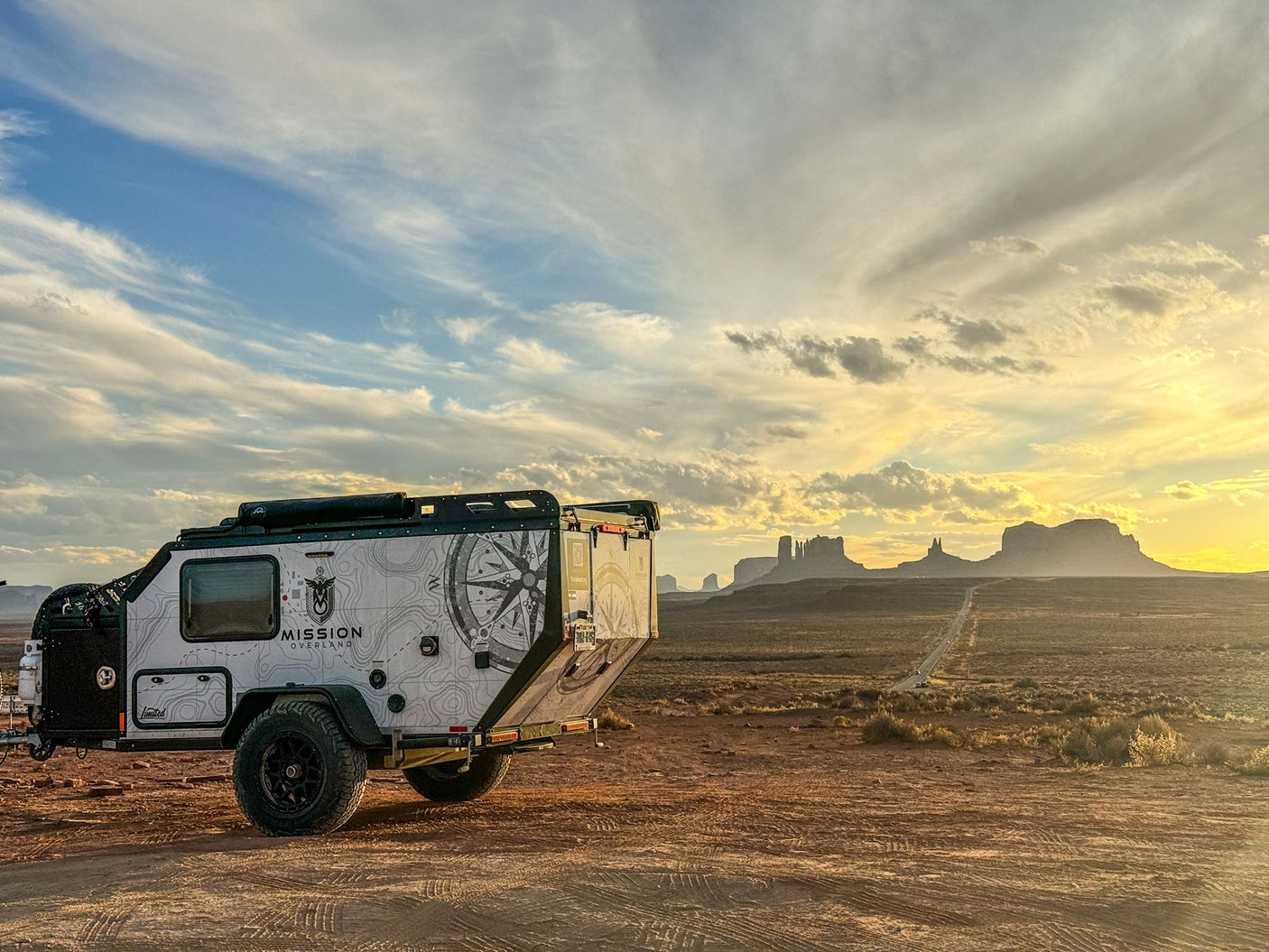 Overland rv rental trailer with unique map design, set against Monument Valley's golden hour sunset.