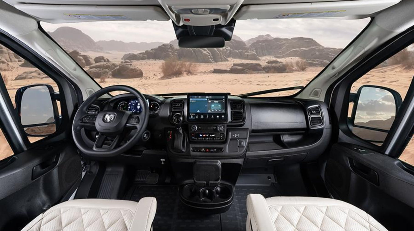 Inside a modern rv rental: the driver's cockpit, showing a detailed dashboard, steering wheel, and a vast desert view.