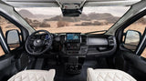 Inside a modern rv rental: the driver's cockpit, showing a detailed dashboard, steering wheel, and a vast desert view.