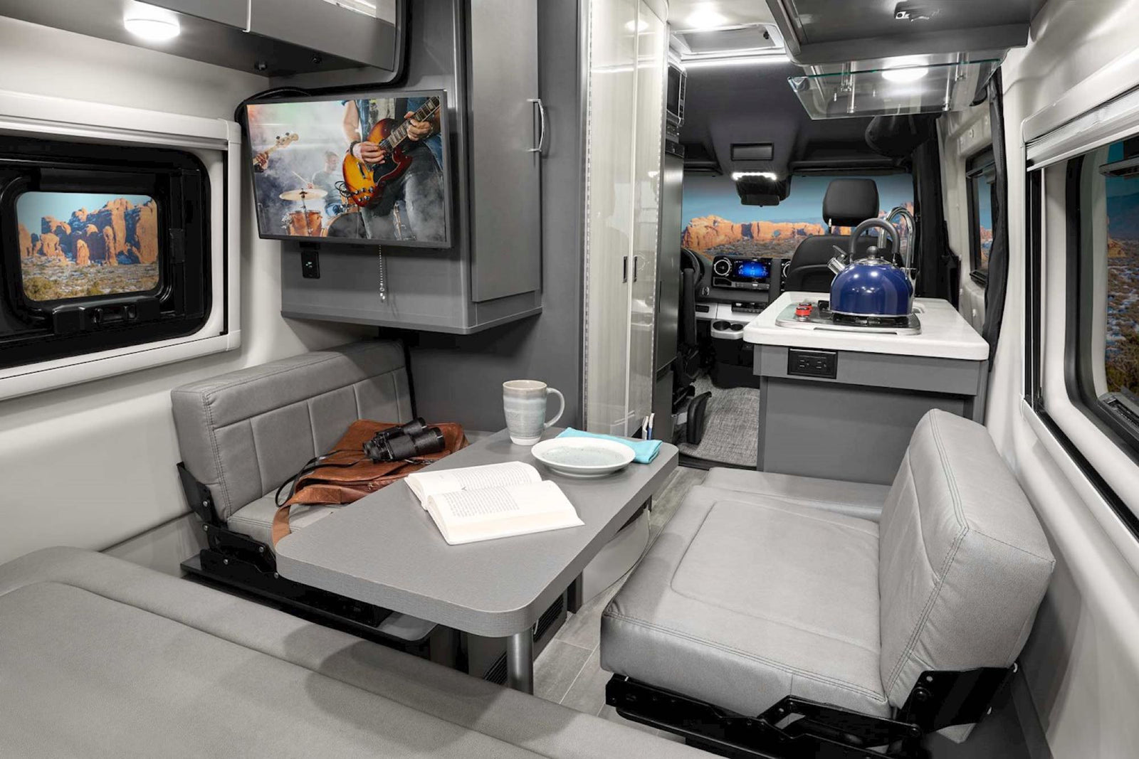 Experience an RV rental: a modern camper van interior featuring a comfortable dinette with TV and a full kitchenette.