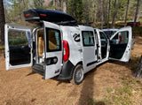 White Ram ProMaster City camper van, doors open, showing its cozy interior. Ideal for an RV rental forest camping trip.