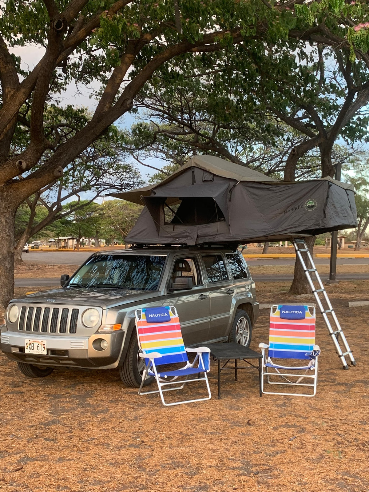 Hawaii camping: Jeep Patriot with a rooftop tent, chairs, and table. Perfect RV rental for your next adventure!