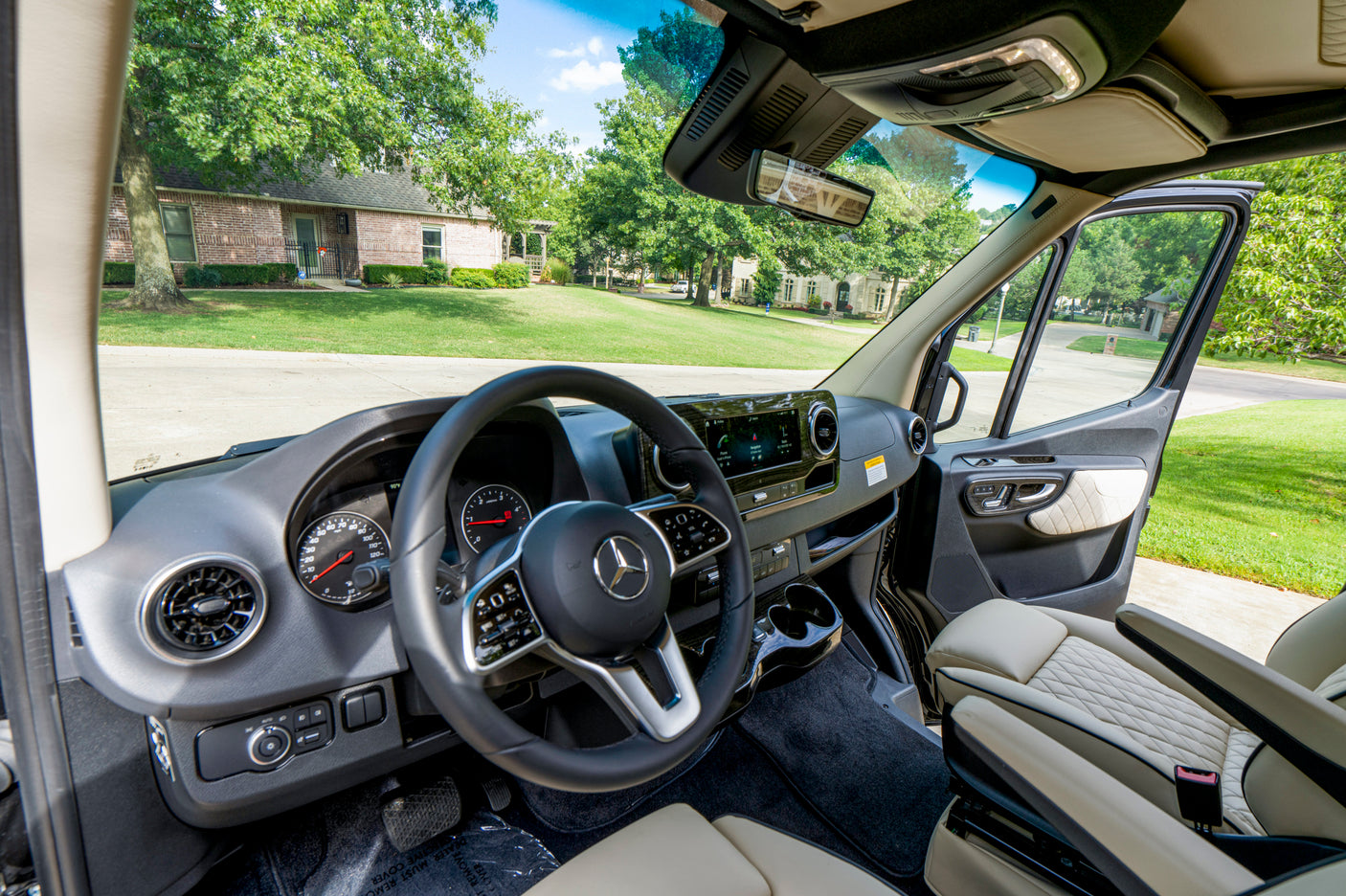 Mercedes-Benz van RV rental interior: Modern dashboard, comfortable passenger seat, and open door view to a street.