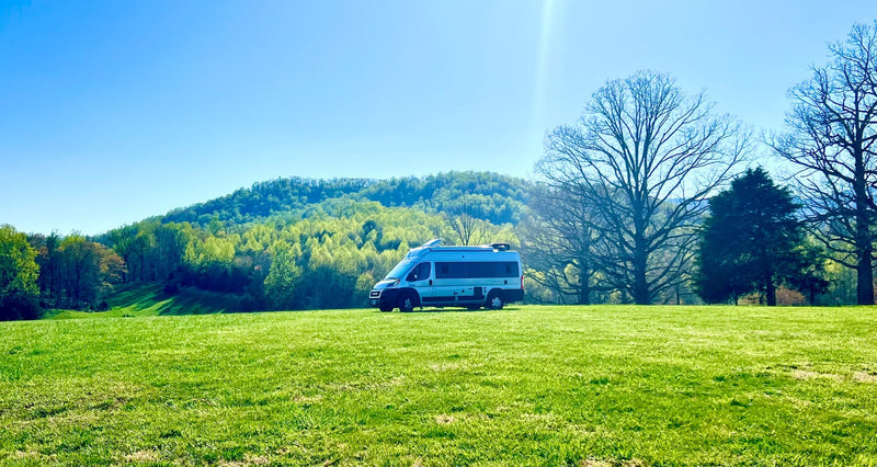  overlooking water.|An RV rental scene: Two people and their dog share coffee and breakfast outside a camper van — photo 6