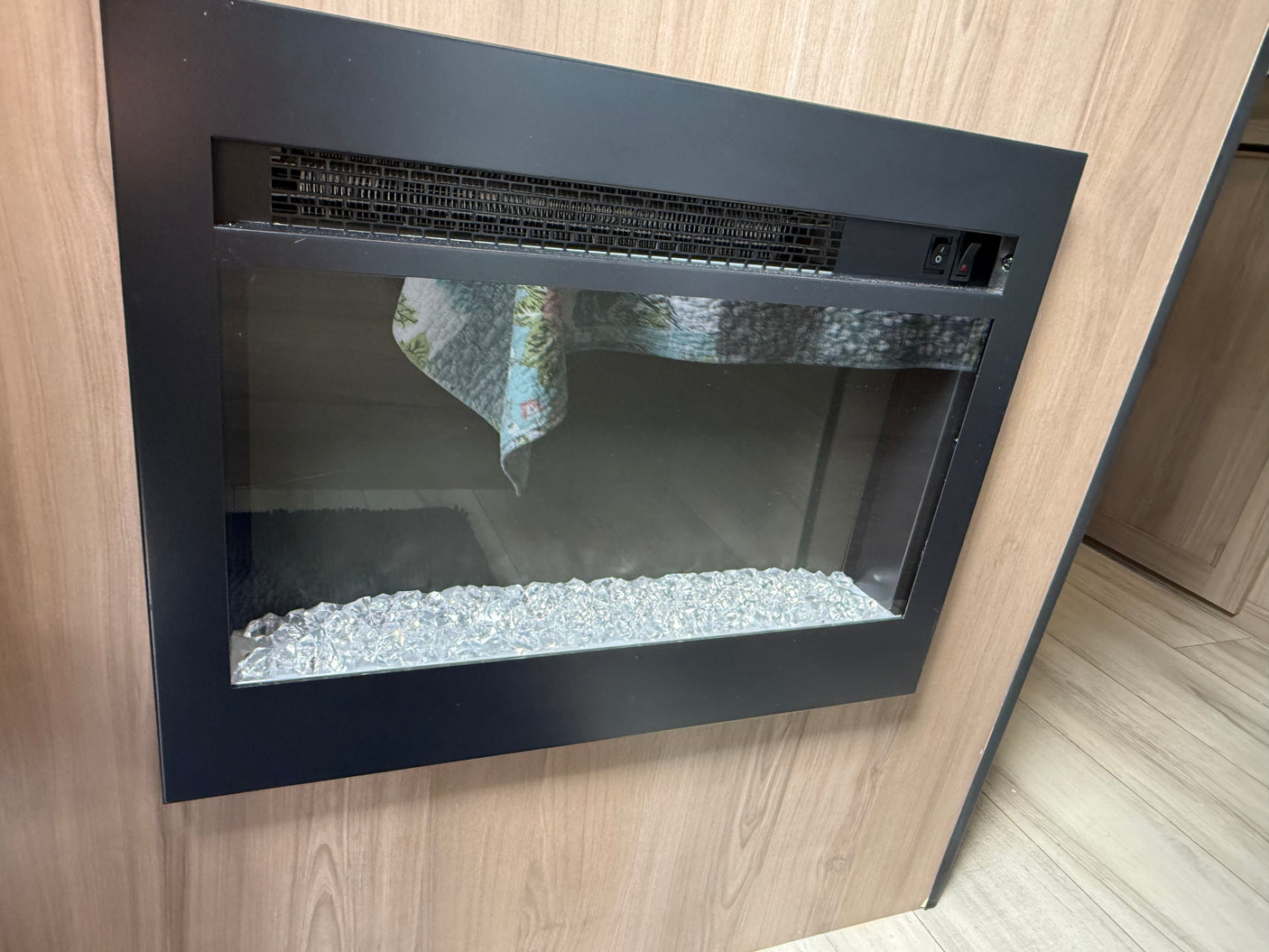 Experience comfort in this RV rental! Features a built-in electric fireplace with a black frame and decorative crystal media.