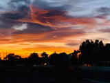 Stunning sunset sky with vibrant orange and red hues over silhouetted trees and homes. Ideal for an RV rental trip!