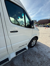 White Mercedes Sprinter RV rental. Side view of this Ascent-TS motorhome conversion parked on a gravel lot under a blue sky.
