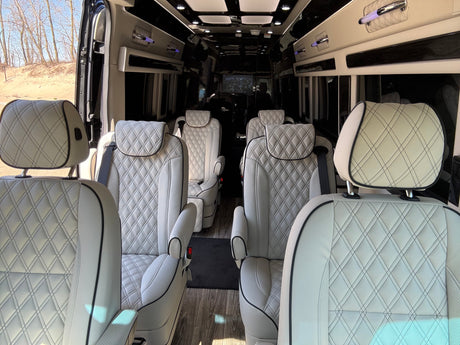 Premium RV rental interior showcasing diamond-stitched leather captain's chairs and spacious private cabin design.