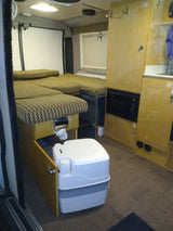 RV rental: Functional camper interior featuring sleeping areas, built-in microwave, and an accessible portable toilet.