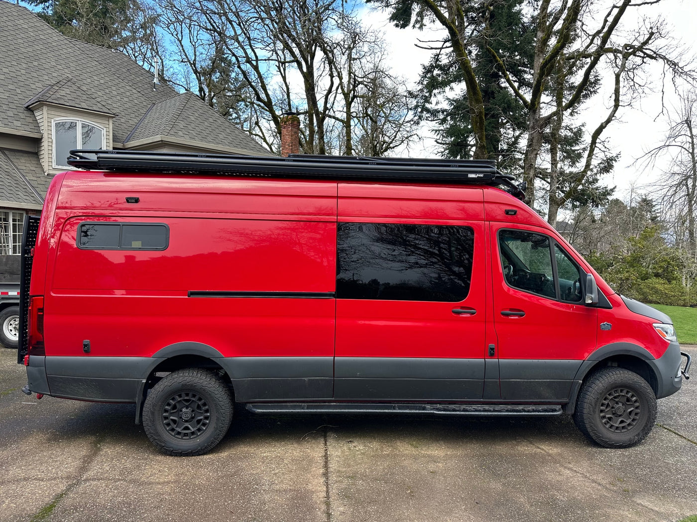 Custom bright red adventure van, ideal for rv rental. Features off-road tires, a roof rack, and a unique look. — photo 5