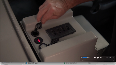 RV rental interior: A hand interacts with a control panel featuring a 12.9V voltmeter and USB charging ports.