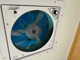 RV rental ceiling fan with blue blades, screen, and controls for IN/OUT airflow and speed, enhancing RV ventilation.