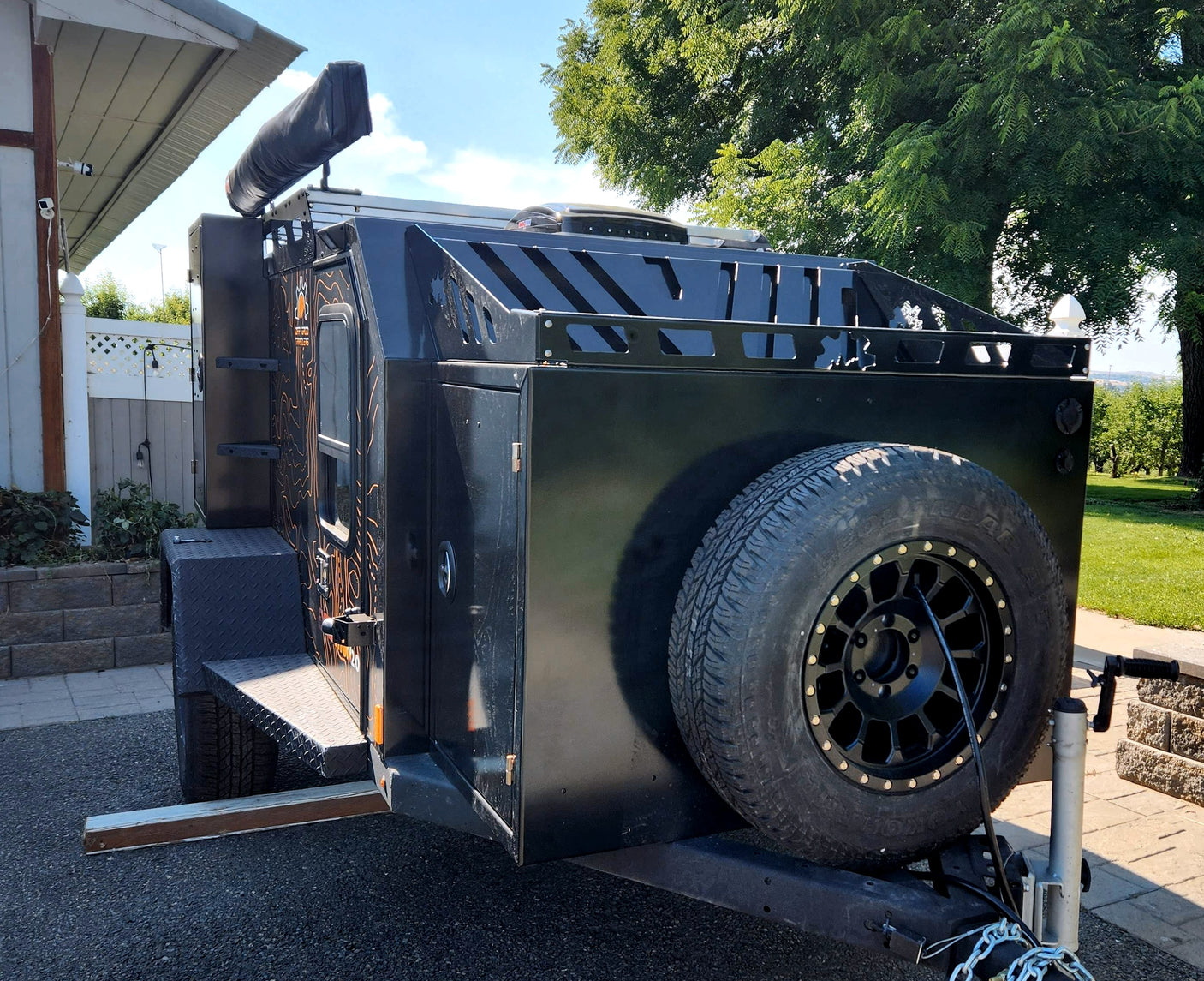 Black off-road adventure trailer, great for rv rental. Features a front spare tire and ample storage.