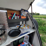 Inside an RV rental, a compact camper kitchen with a stove, cookware, and freeze-dried Chicken & Dumplings for adventure meals.