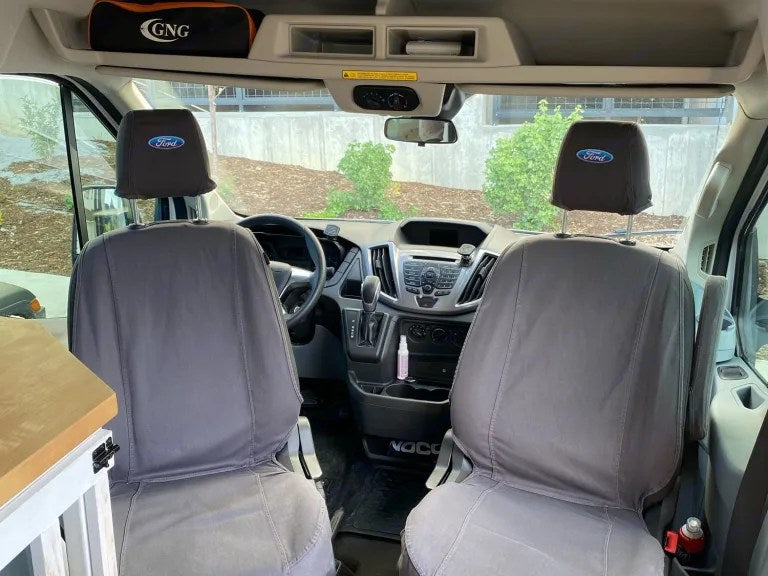 Inside an RV rental van: two gray Ford-branded front seats, dashboard, and overhead storage for a road trip. — photo 3