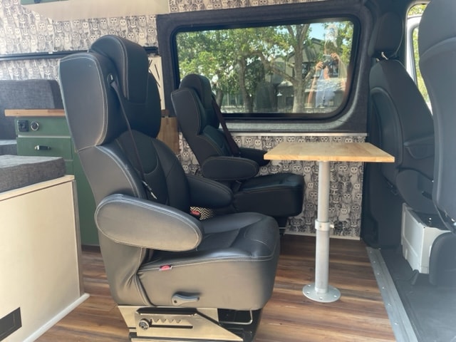 RV rental: Van interior with comfy swivel seats, a compact dining table, and playful owl decor. Ready for travel. — photo 2