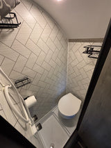 Inside an **rv rental** bathroom: compact design with a toilet, shower, storage shelves, and modern patterned tiled walls.