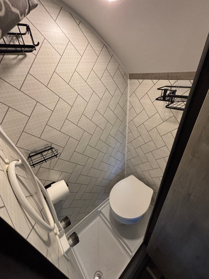 Inside an **rv rental** bathroom: compact design with a toilet, shower, storage shelves, and modern patterned tiled walls. — photo 15