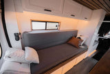 Cozy RV rental interior with grey bench seating, overhead cabinets, a small window, and a control panel on the wall.