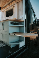 RV rental: Inside a stylish camper van with light blue cabinets, wood countertops, and a clever pull-out table.