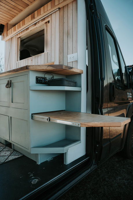 RV rental: Inside a stylish camper van with light blue cabinets, wood countertops, and a clever pull-out table.
