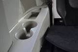 RV rental interior showing a light-colored console with cup holders, storage, and a speaker, next to a black seat.