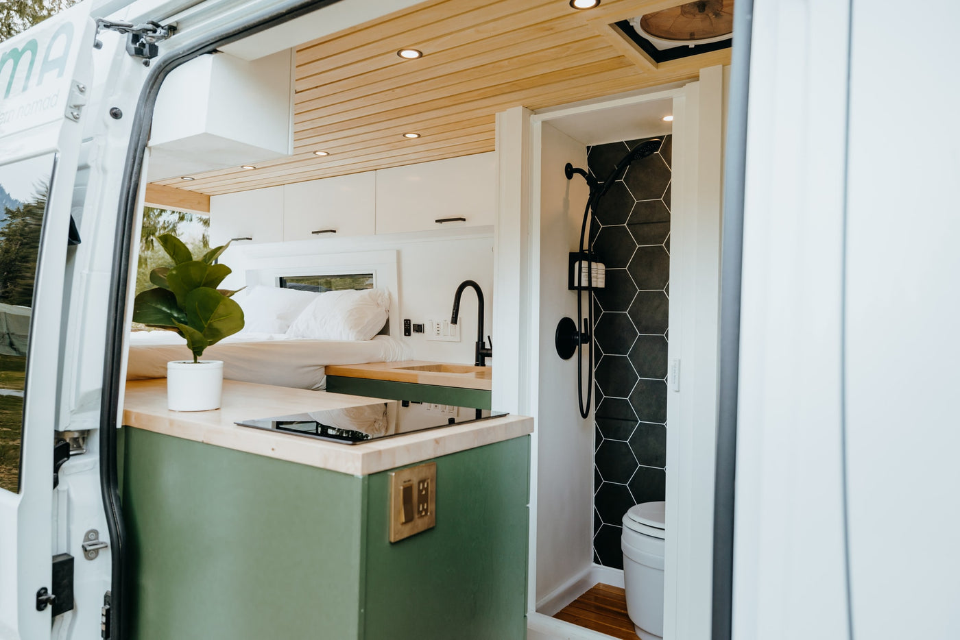 Stylish RV rental interior with kitchen, comfy bed, and a sleek bathroom featuring hexagon tiles. Perfect van conversion for mobile living. — photo 2
